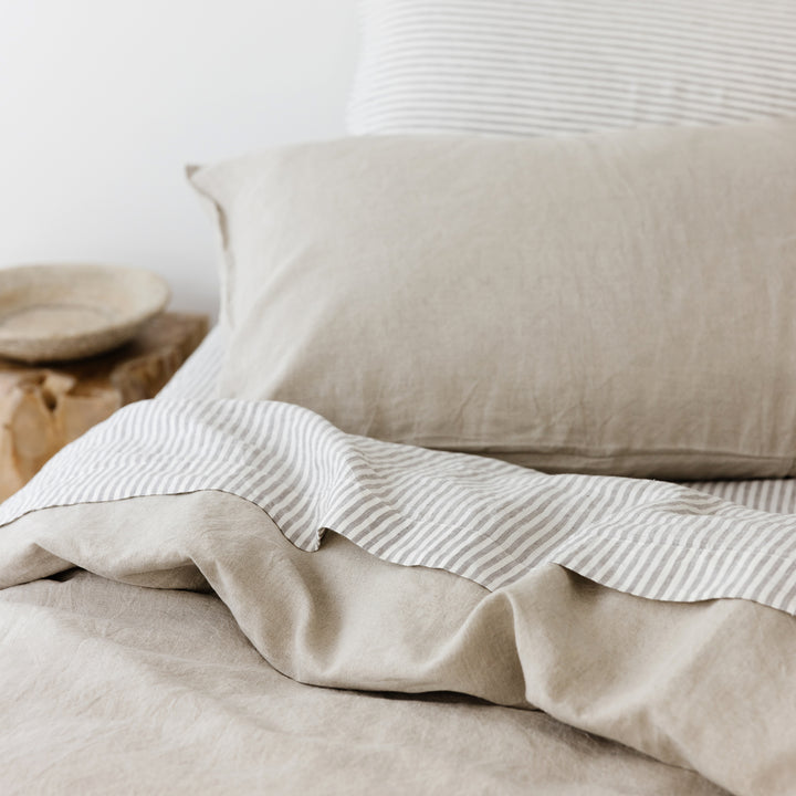 Foxtrot Home French Flax Linen styled in a bedroom with Natural Duvet, Grey Stripes Sheets Set and Pillowcases.