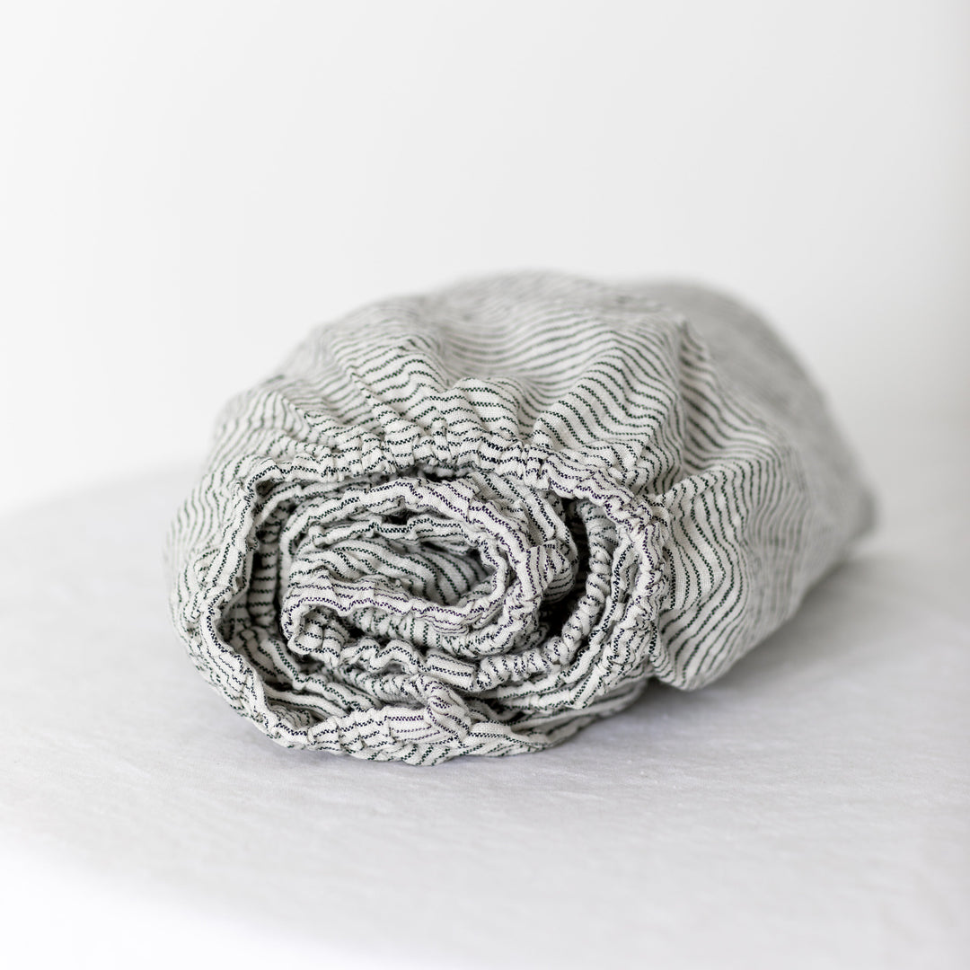 Foxtrot Home French Flax Linen styled in a baby's bedroom with Pinstripes Cot Sheet and Bassinet Sheets.