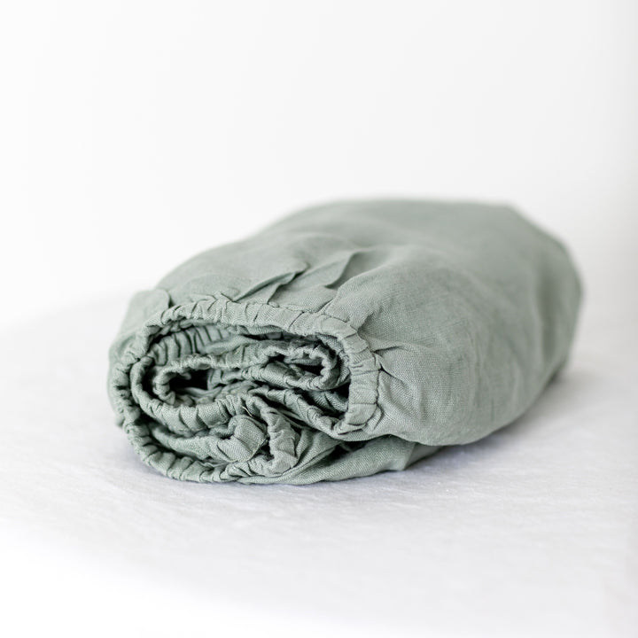 Foxtrot Home French Flax Linen styled in a baby's bedroom with Sage Green Cot Sheet and Bassinet Sheets.