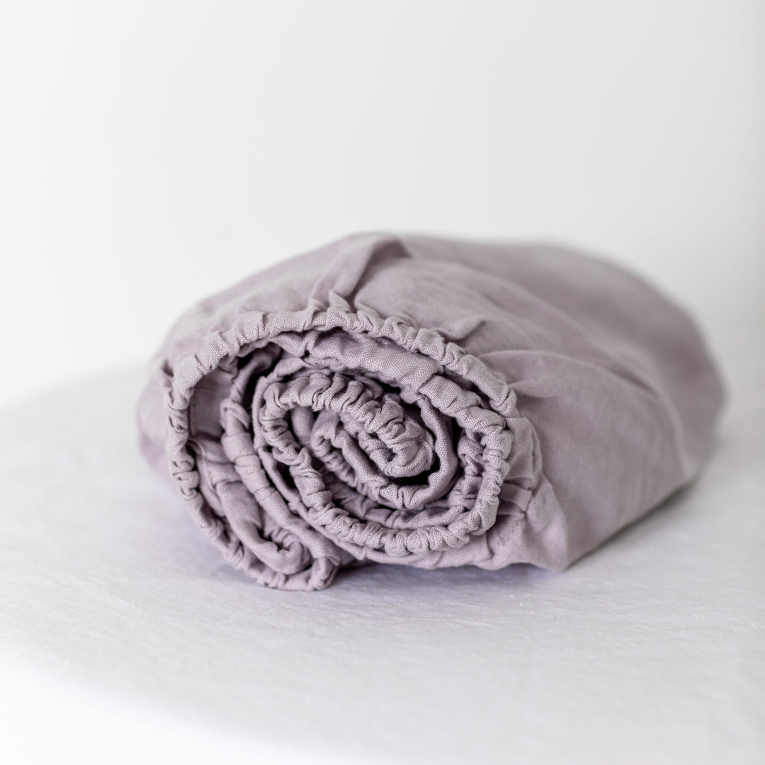 Foxtrot Home French Flax Linen styled in a baby's bedroom with Lilac Purple Cot Sheet and Bassinet Sheets.