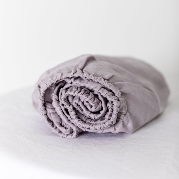 Foxtrot Home French Flax Linen styled in a baby's bedroom with Lilac Purple Cot Sheet and Bassinet Sheets.