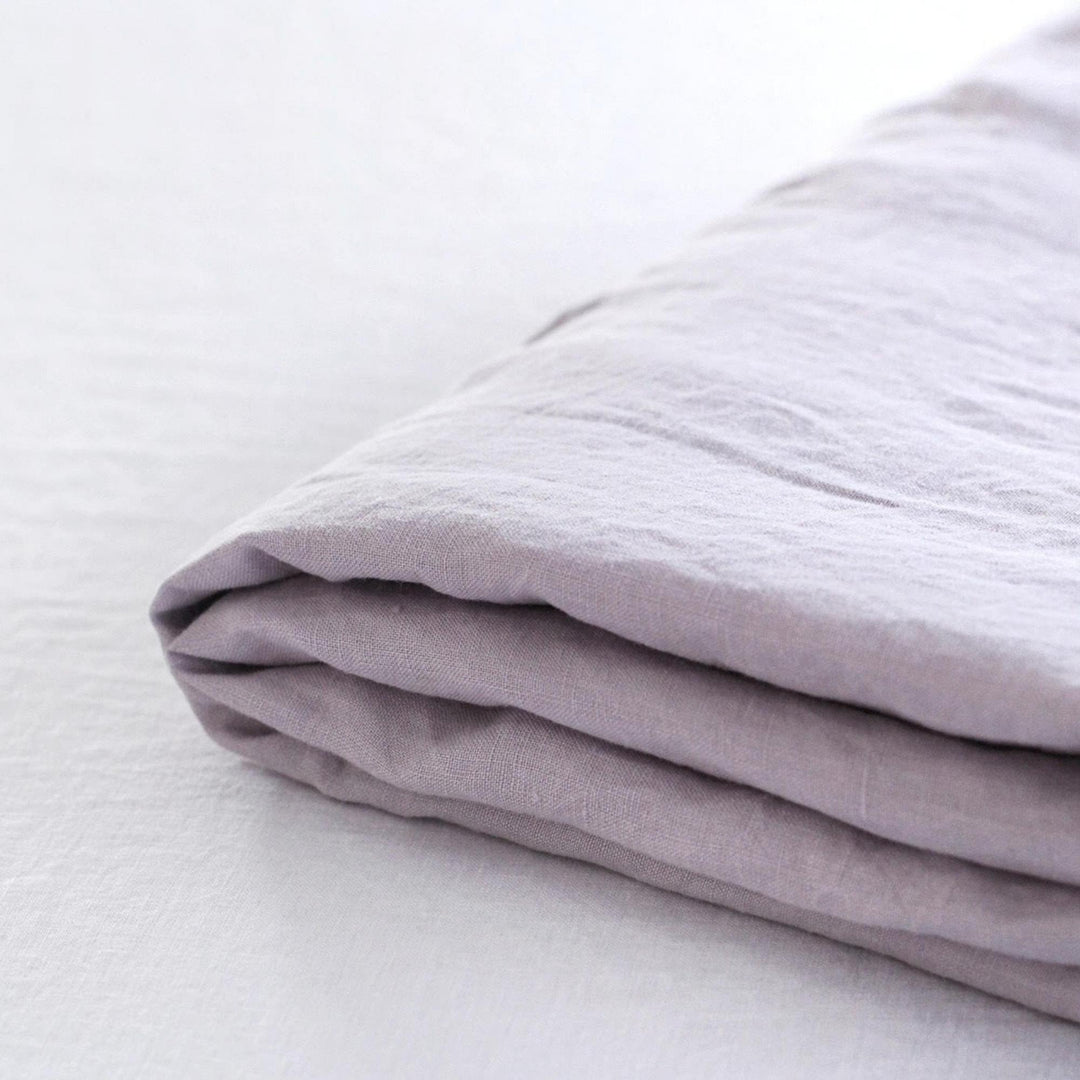 Foxtrot Home French Flax Linen styled in a baby's bedroom with Lilac Purple Cot Sheet and Bassinet Sheets.