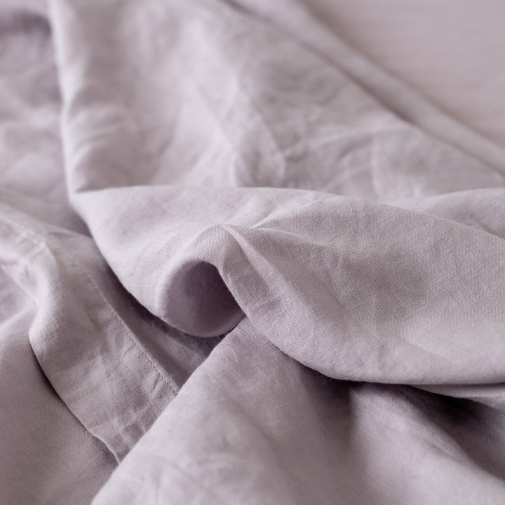 Foxtrot Home French Flax Linen styled in a baby's bedroom with Lilac Purple Cot Sheet and Bassinet Sheets.