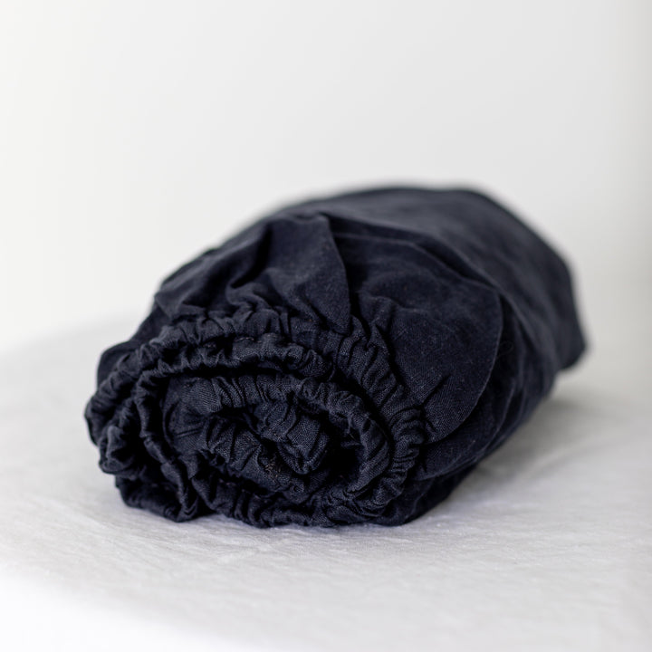 Foxtrot Home French Flax Linen styled in a baby's bedroom with Midnight Blue Cot Sheet and Bassinet Sheets.