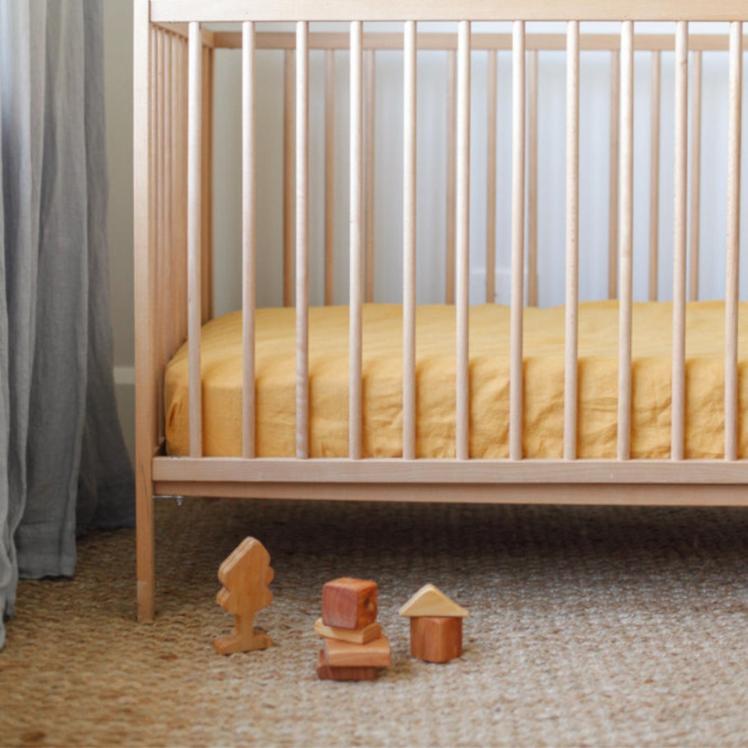 Foxtrot Home French Flax Linen styled in a baby's bedroom with Mustard Yellow Cot Sheet and Bassinet Sheets.