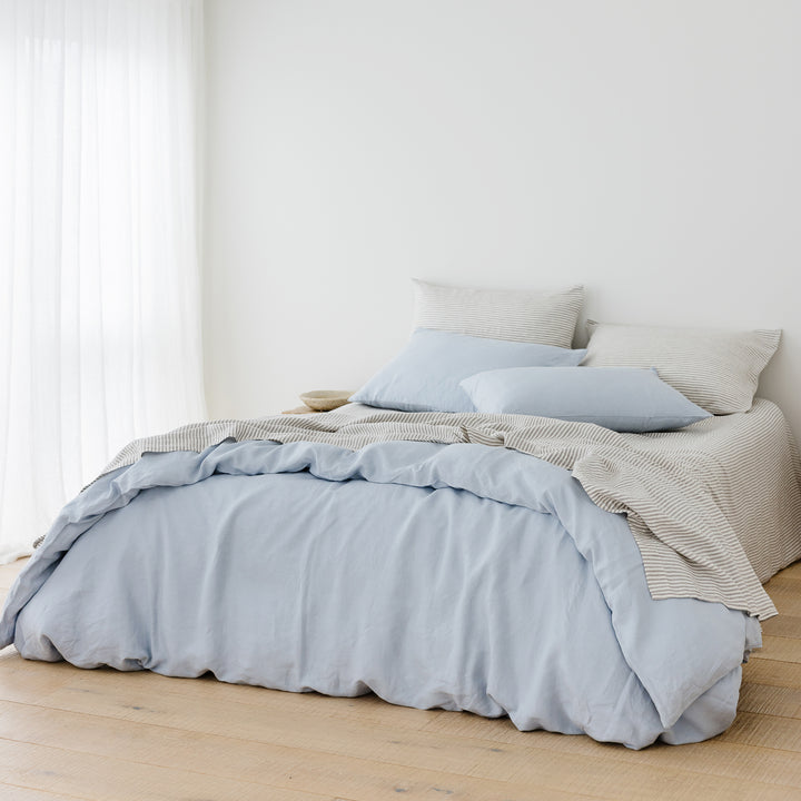 Foxtrot Home French Flax Linen styled in a bedroom with Powder Blue Duvet, Grey Stripes Sheets Sets and Pillowcases.