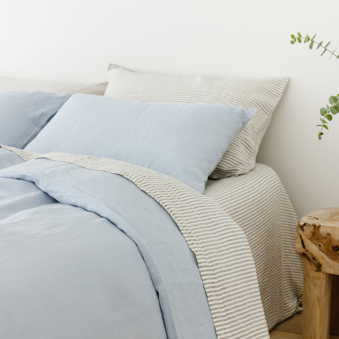 Foxtrot Home French Flax Linen styled in a bedroom with Powder Blue Duvet, Grey Stripes Sheets Sets and Pillowcases.