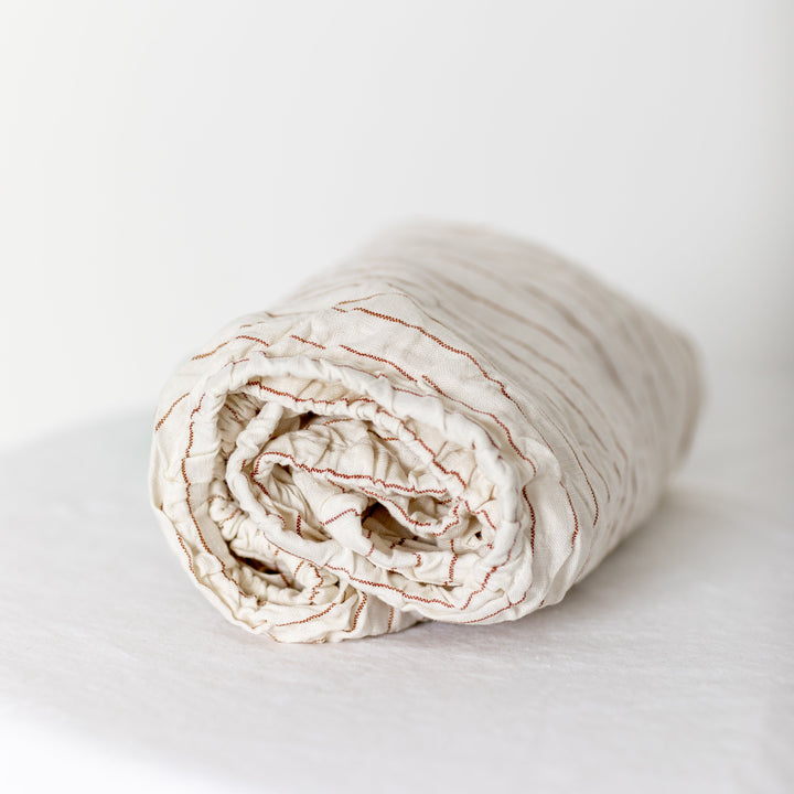 Foxtrot Home French Flax Linen styled in a baby's bedroom with Tobacco Stripes Cot Sheet and Bassinet Sheets.