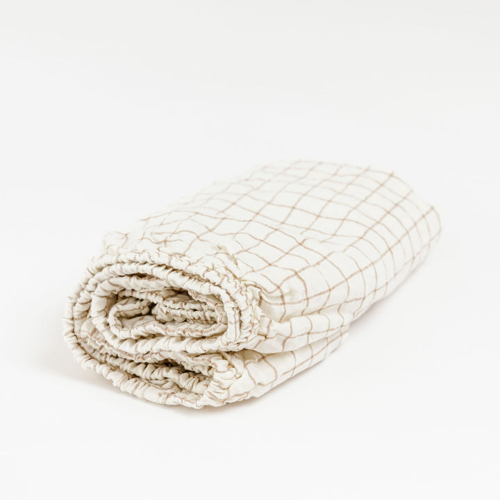 Foxtrot Home French Flax Linen styled in a baby's bedroom with Malt Brown Grid Cot Sheet and Bassinet Sheets.