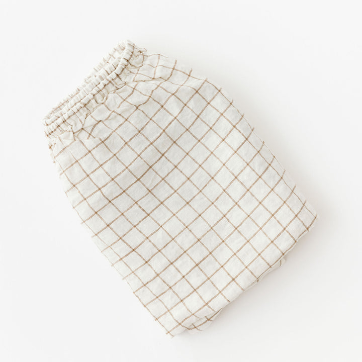 Foxtrot Home French Flax Linen styled in a baby's bedroom with Malt Brown Grid Cot Sheet and Bassinet Sheets.