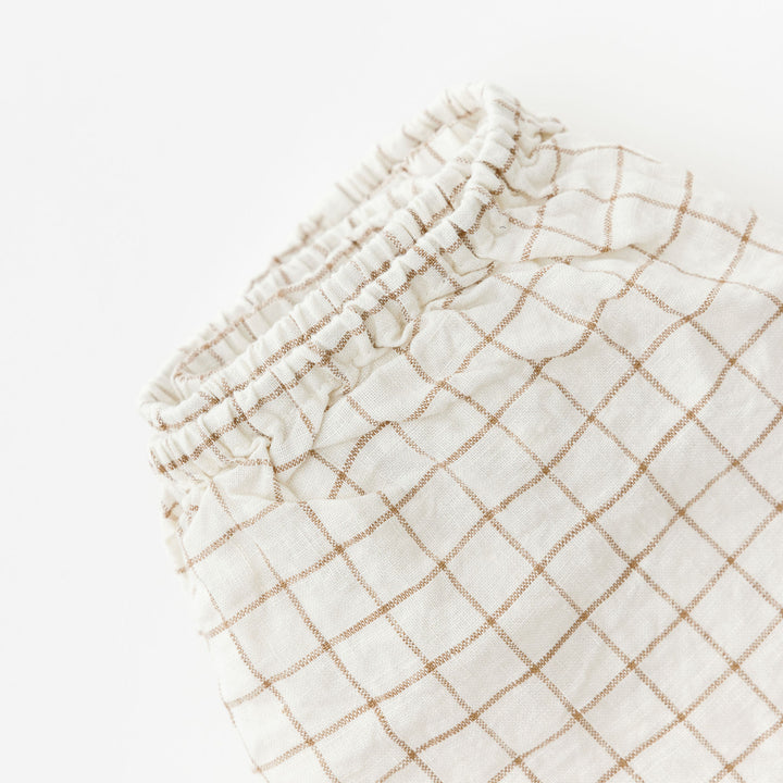 Foxtrot Home French Flax Linen styled in a baby's bedroom with Malt Brown Grid Cot Sheet and Bassinet Sheets.