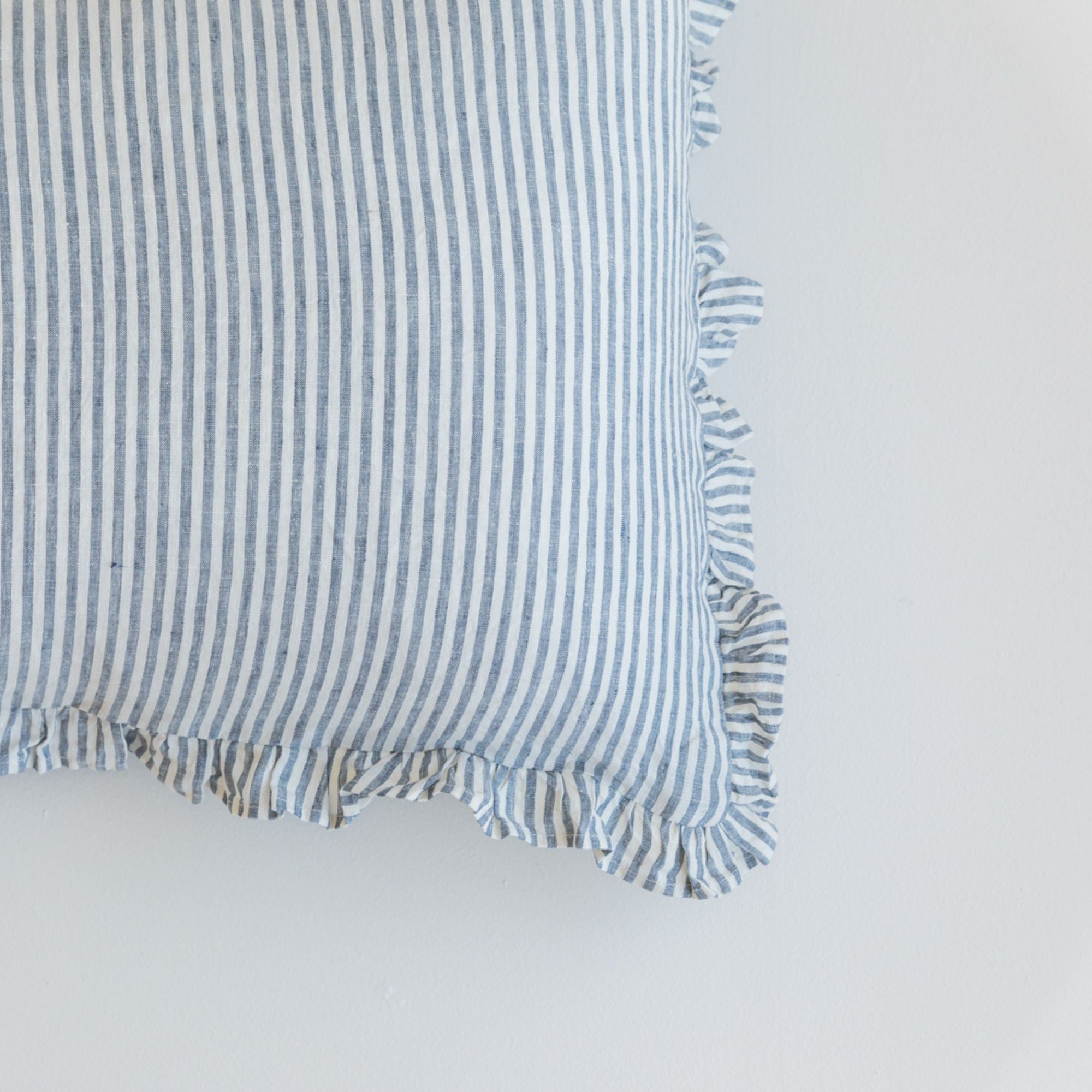 Foxtrot Home French Flax Linen styled in a bedroom with a Navy Stripes Ruffles Cushion Cover