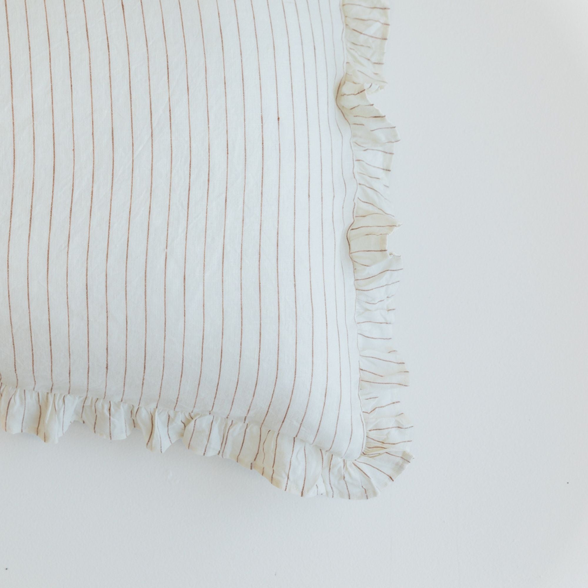 Foxtrot Home French Flax Linen styled in a bedroom with a Tobacco Stripes Ruffles Cushion Cover
