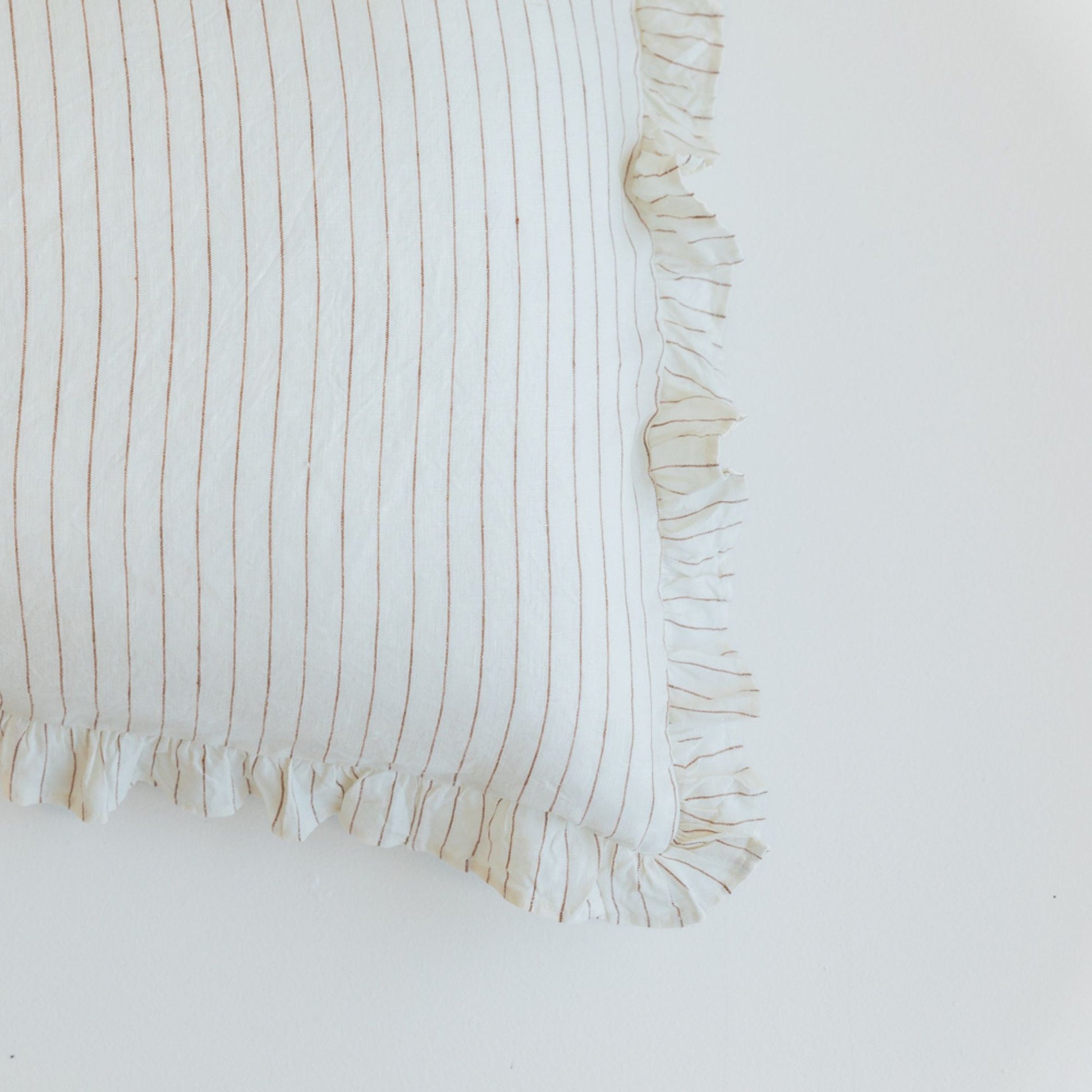 Foxtrot Home French Flax Linen styled in a bedroom with a Tobacco Stripes Ruffles Cushion Cover