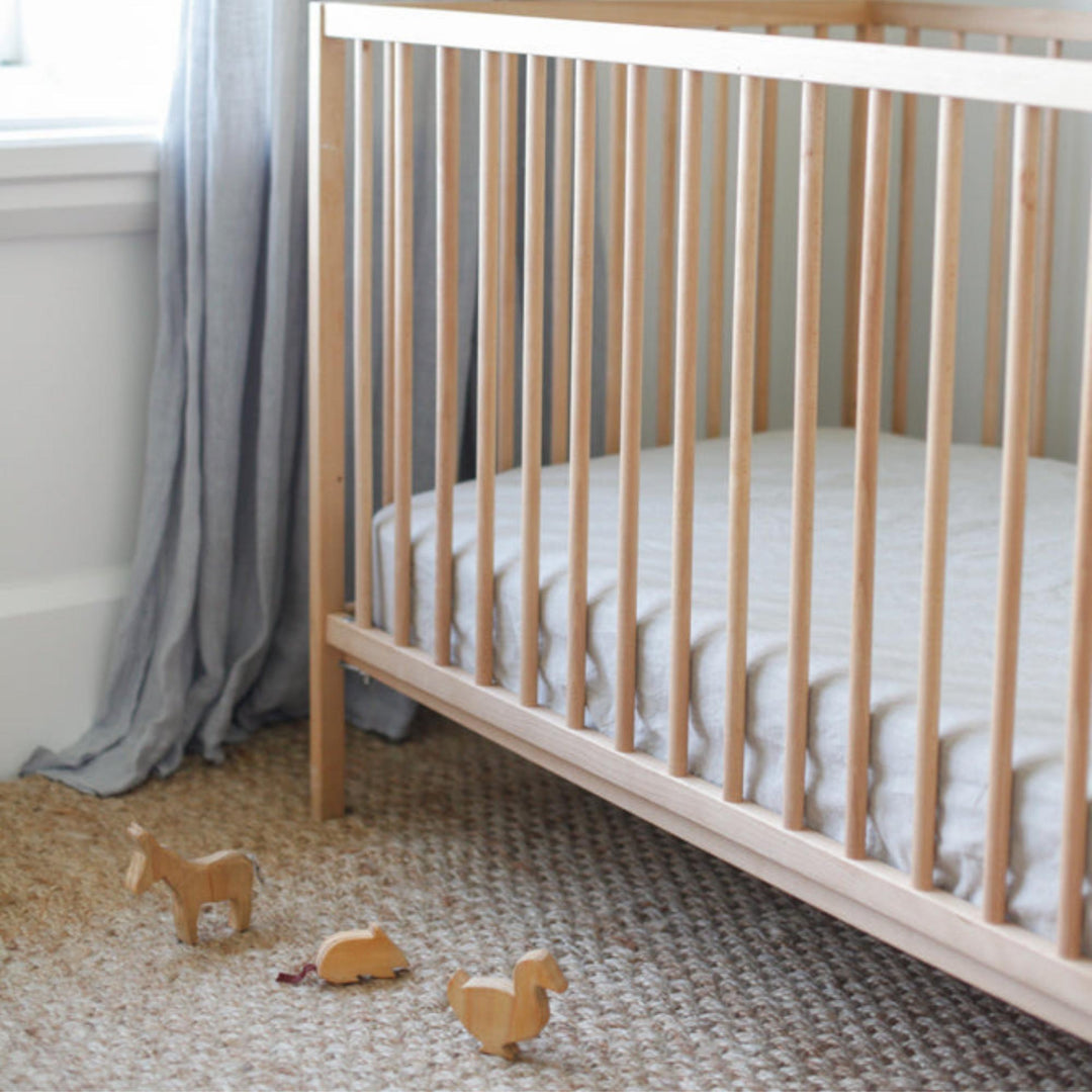 Foxtrot Home French Flax Linen styled in a baby's bedroom with Natural Cot Sheet and Bassinet Sheets.