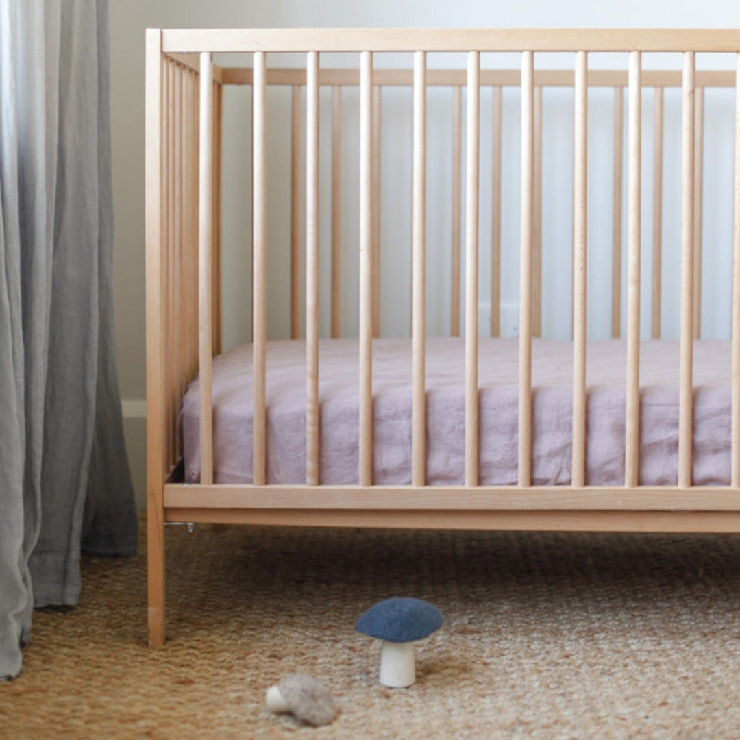 Foxtrot Home French Flax Linen styled in a baby's bedroom with Rosewood Pink Cot Sheet and Bassinet Sheets.