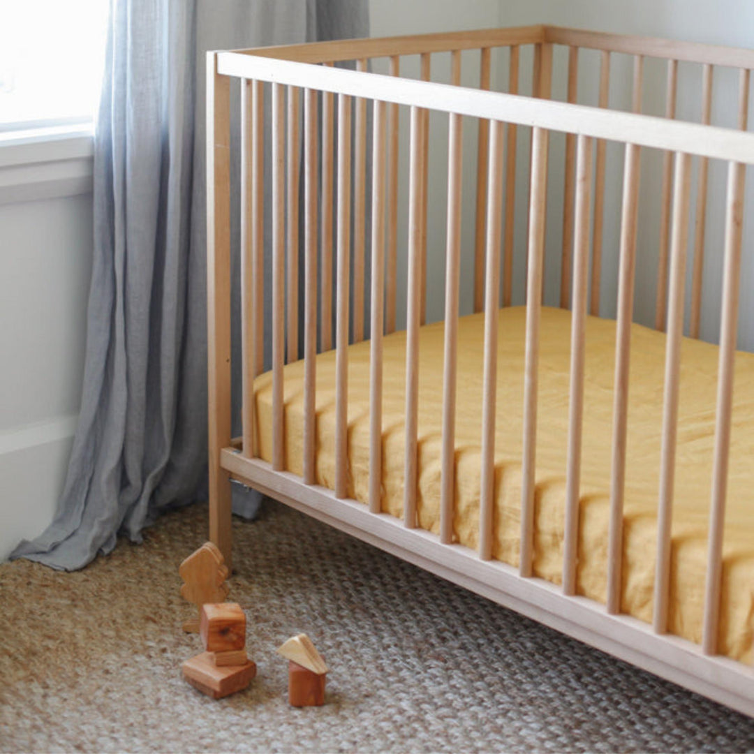 Foxtrot Home French Flax Linen styled in a baby's bedroom with Mustard Yellow Cot Sheet and Bassinet Sheets.