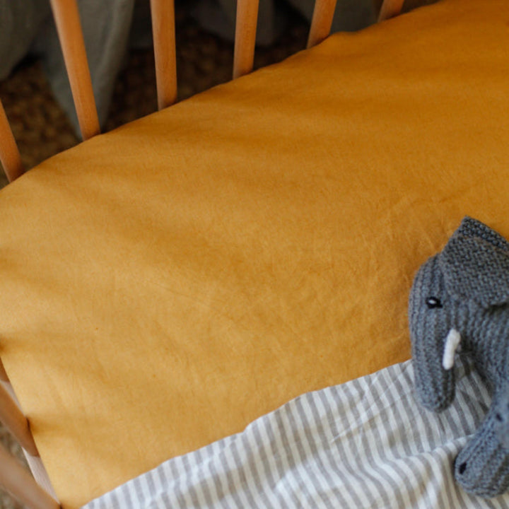 Foxtrot Home French Flax Linen styled in a baby's bedroom with Mustard Yellow Cot Sheet and Bassinet Sheets.