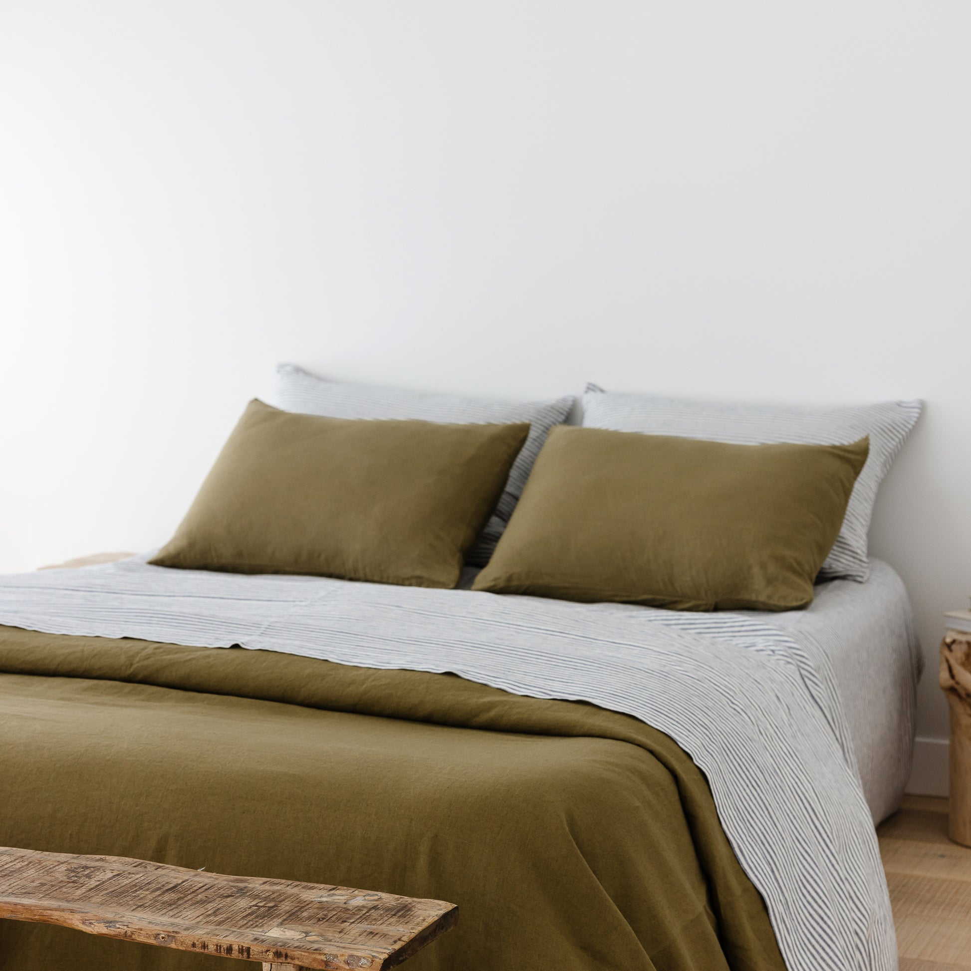 Foxtrot Home French Flax Linen styled in a bedroom with Olive Green Duvet, Navy Blue Sheets Set and Pillowcases.
