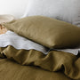 Foxtrot Home French Flax Linen styled in a bedroom with Olive Green Duvet, Navy Blue Sheets Set and Pillowcases.