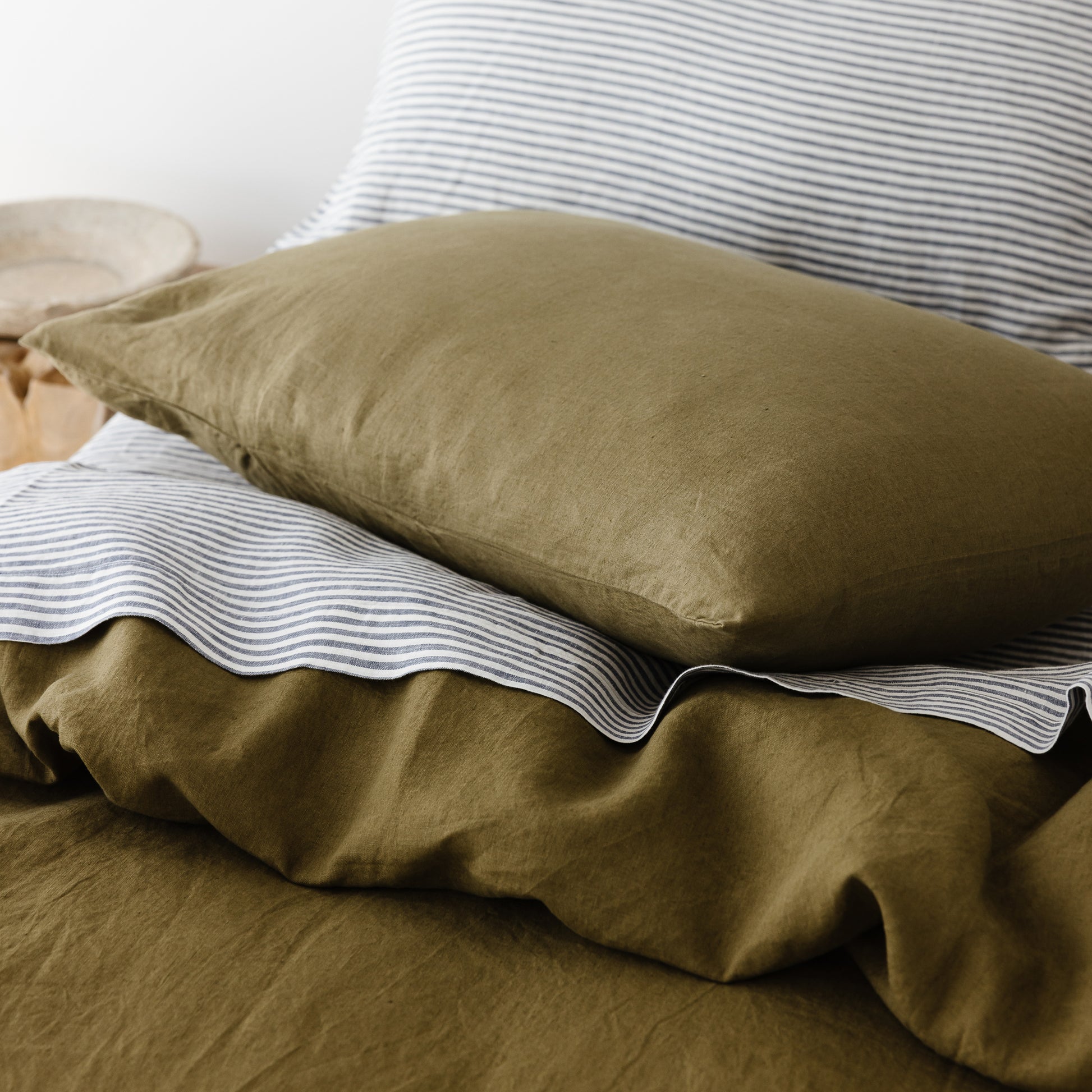 Foxtrot Home French Flax Linen styled in a bedroom with Olive Green Duvet, Navy Blue Sheets Set and Pillowcases.