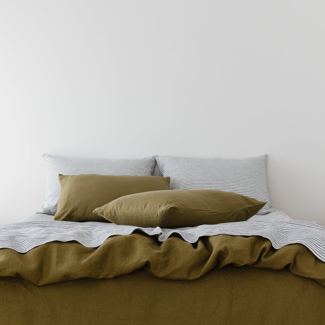 Foxtrot Home French Flax Linen styled in a bedroom with Olive Green Duvet, Navy Blue Sheets Set and Pillowcases.