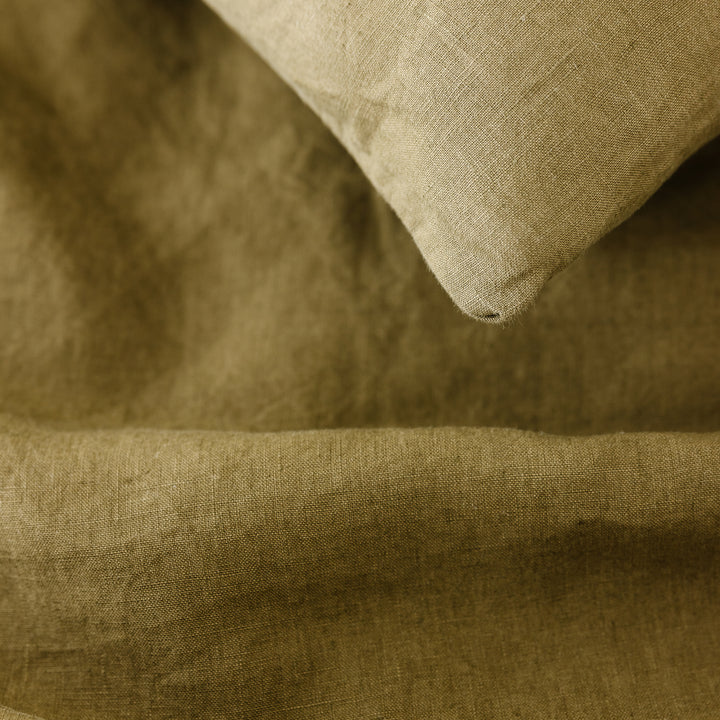 Foxtrot Home French Flax Linen styled in a bedroom with Olive Green Duvet, Navy Blue Sheets Set and Pillowcases.