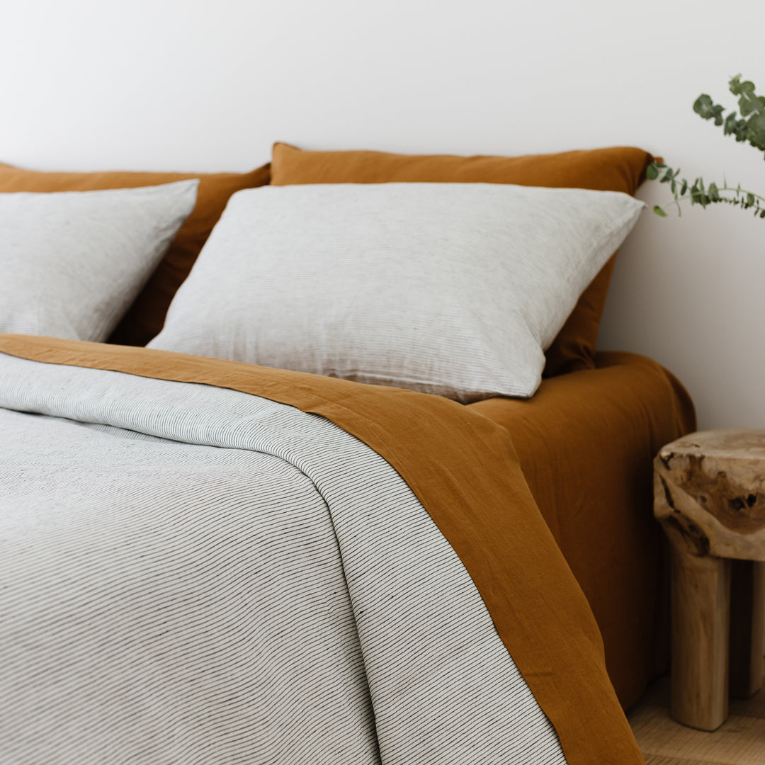 Foxtrot Home French Flax Linen styled in a bedroom with Pinstripes Duvet, Tobacco Sheets Set and Pillowcases.