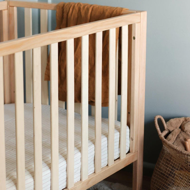 Foxtrot Home French Flax Linen styled in a baby's bedroom with Tobacco Stripes Cot Sheet and Bassinet Sheets.