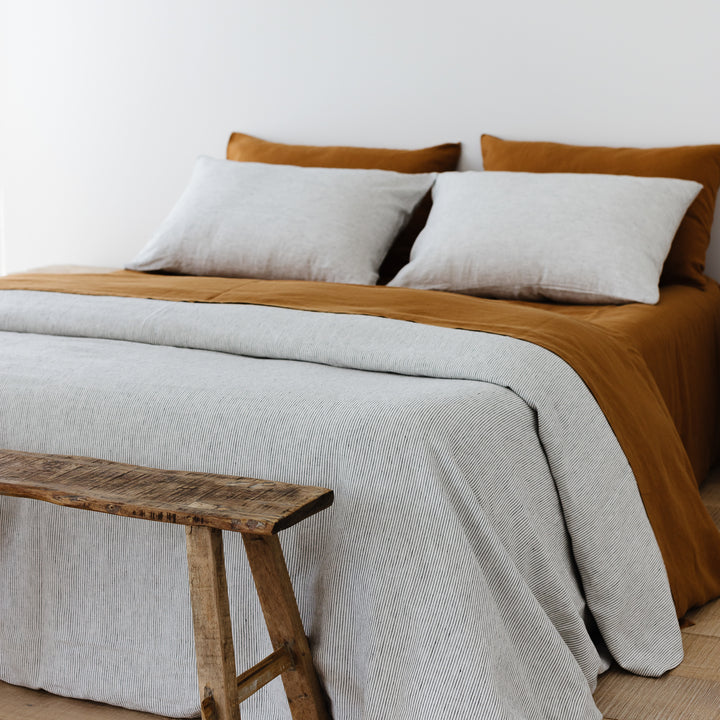 Foxtrot Home French Flax Linen styled in a bedroom with Pinstripes Duvet, Tobacco Sheets Set and Pillowcases.