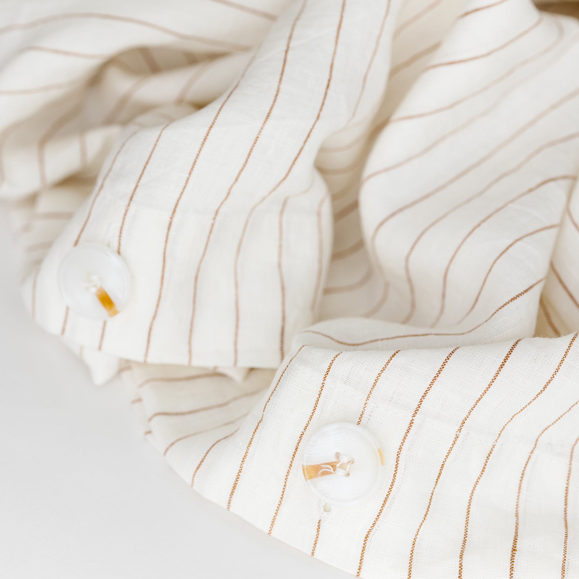 Foxtrot Home French Flax Linen styled in a bedroom with Tobacco Stripes Duvet, Oat Sheets Set and Pillowcases.