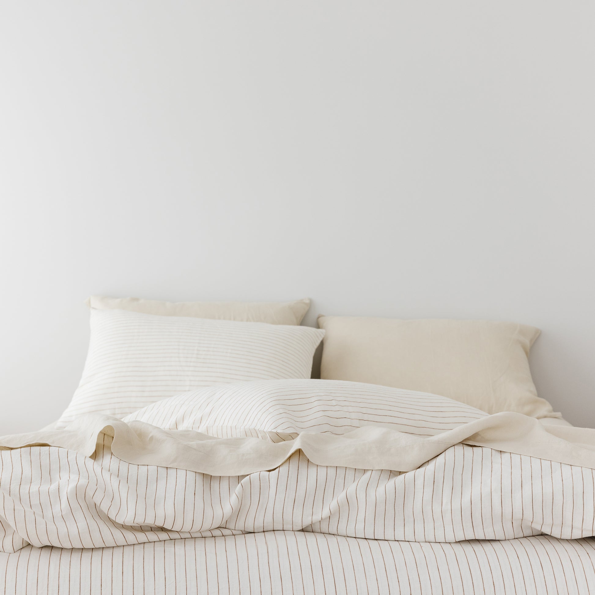 Foxtrot Home French Flax Linen styled in a bedroom with Tobacco Stripes Duvet, Oat Sheets Set and Pillowcases.