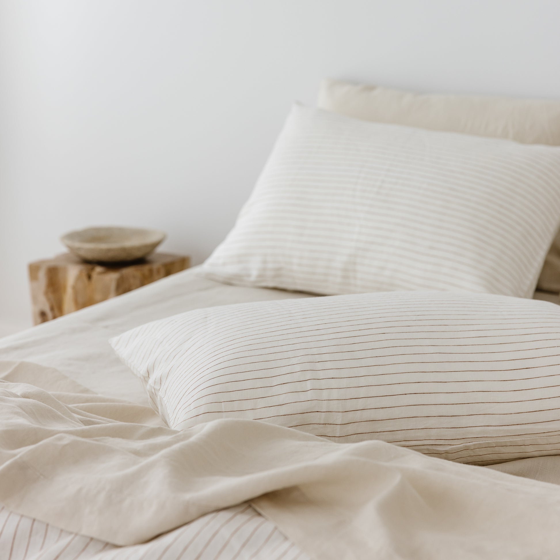 Foxtrot Home French Flax Linen styled in a bedroom with Tobacco Stripes Duvet, Oat Sheets Set and Pillowcases.