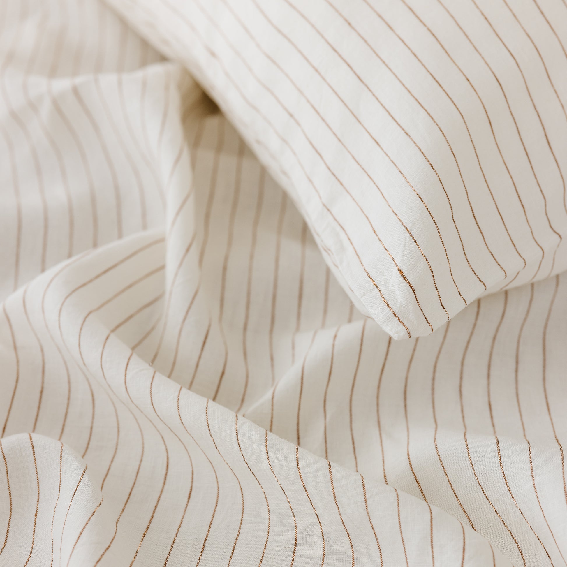 Foxtrot Home French Flax Linen styled in a bedroom with Tobacco Stripes Duvet, Oat Sheets Set and Pillowcases.