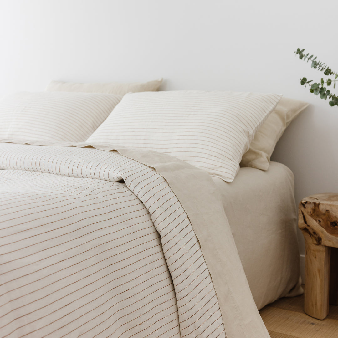 Foxtrot Home French Flax Linen styled in a bedroom with Tobacco Stripes Duvet, Oat Sheets Set and Pillowcases.