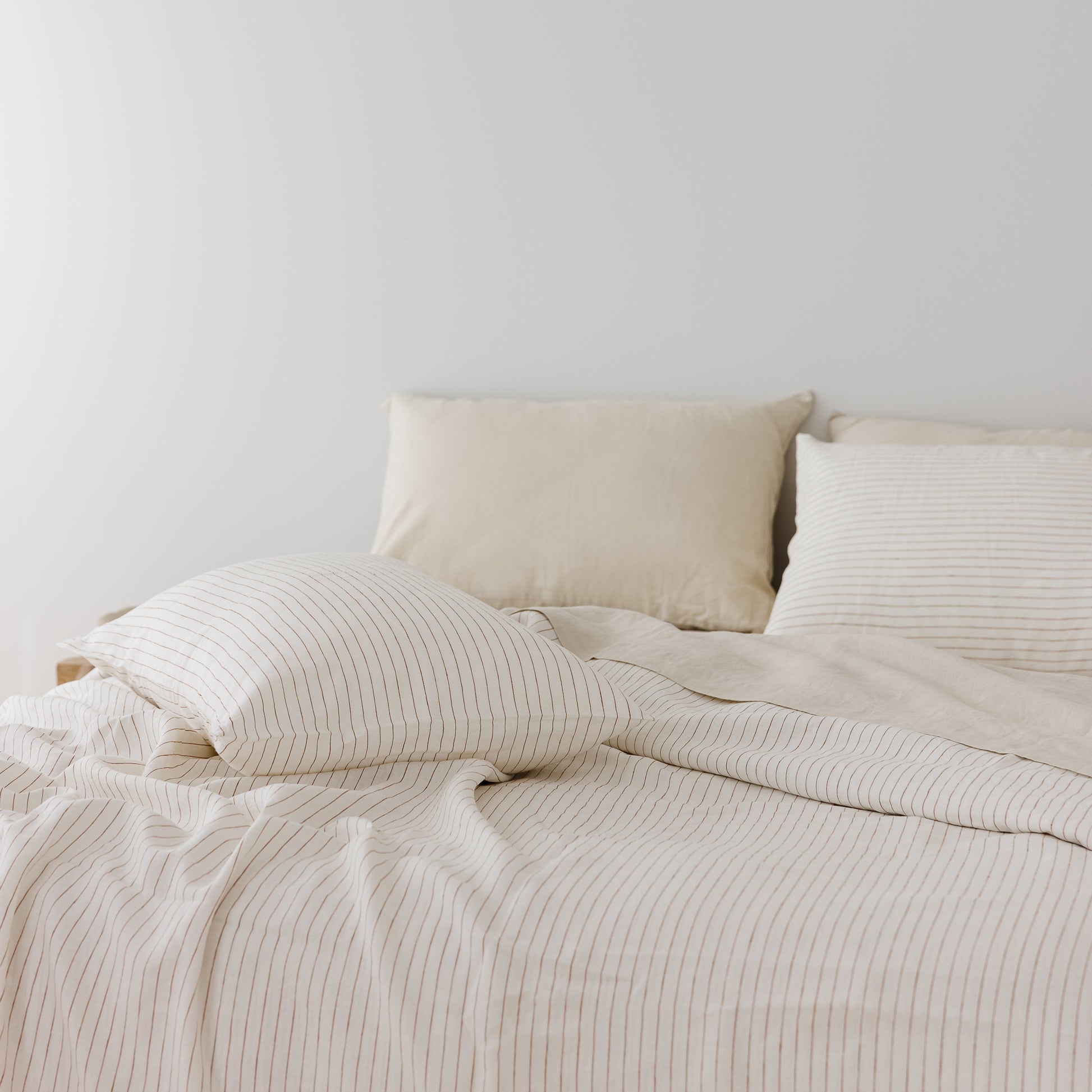 Foxtrot Home French Flax Linen styled in a bedroom with Tobacco Stripes Duvet, Oat Sheets Set and Pillowcases.