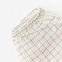 Foxtrot Home French Flax Linen styled in a baby's bedroom with Malt Brown Grid Cot Sheet and Bassinet Sheets.